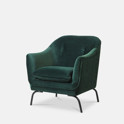 Large emerald green velvet armchair with four black metal legs.