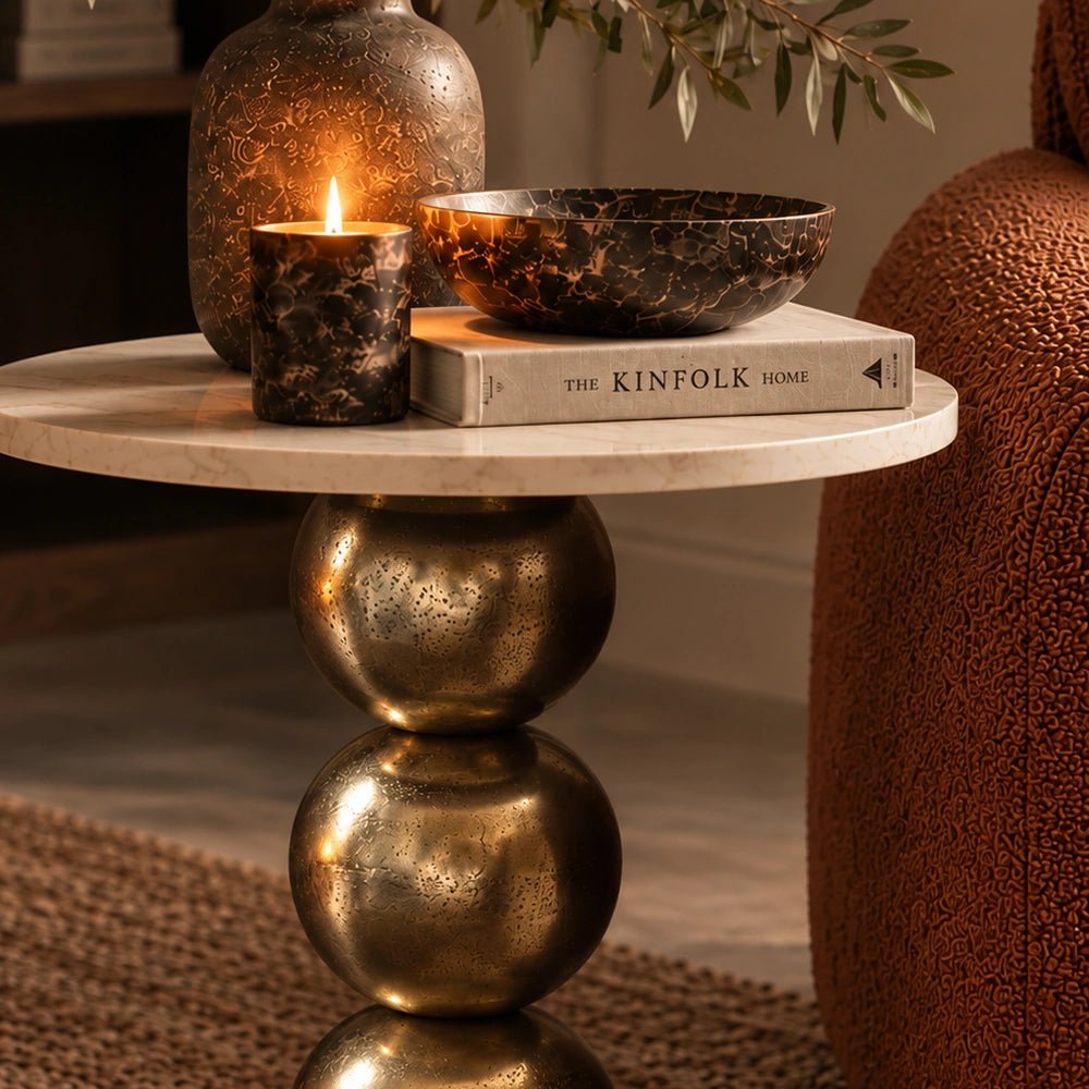 Close-up of the Chelsea Marble Side Table showing the round tabletop with books, candle and bowl above its sculptural stacked pedestal in a styled interior.