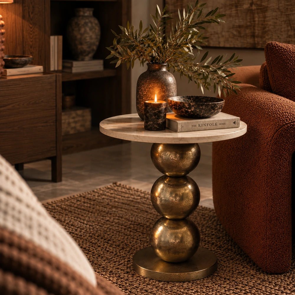 Chelsea Marble Side Table shown from the front with stacked sculptural spheres, styled with books, candle and vase in a warm neutral living room.