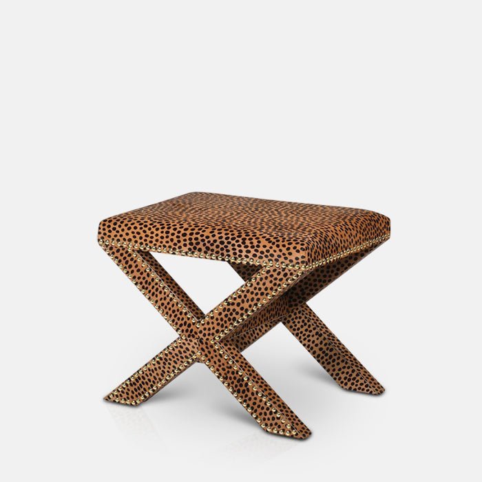 Cutout of Chester Leopard Print Stool, a leather upholstered stool with leopard print design. crossed legs and stud detail.