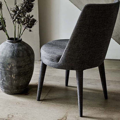 The tall curved back and round seat on a grey upholstered chair.