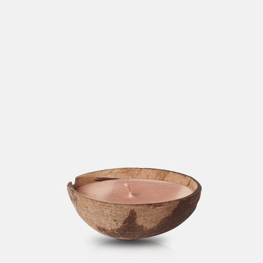 Orangey-pink coloured scented candle poured into half a coconut shell