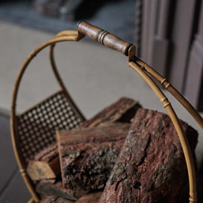 The Cohen Log Holder, a bamboo style with a curved handle, filled with chopped logs.