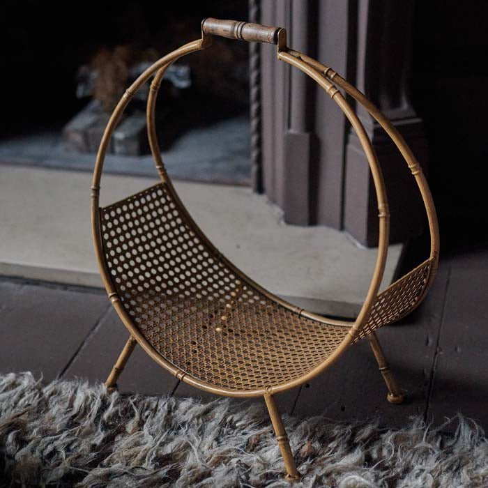 The Cohen Log Holder, a circular bamboo style log holder with a rattan base sat on a shaggy rug.