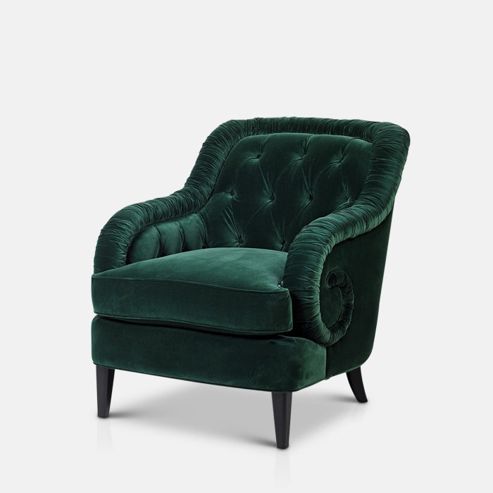 Green velvet armchair with rouched edges and tall back on four black legs