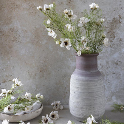 Styled image of an ombre stoneware vase with a faux bouquet of flowers including artificial cream cosmos flowers.