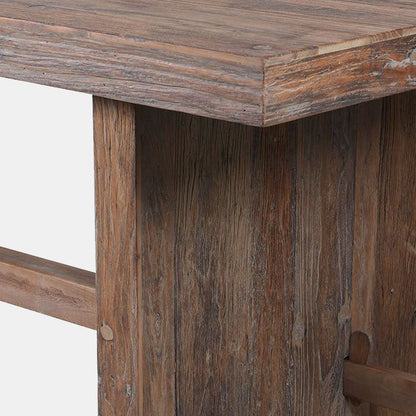 Chunky wooden table top resting on a chunky leg with a beam running through its centre
