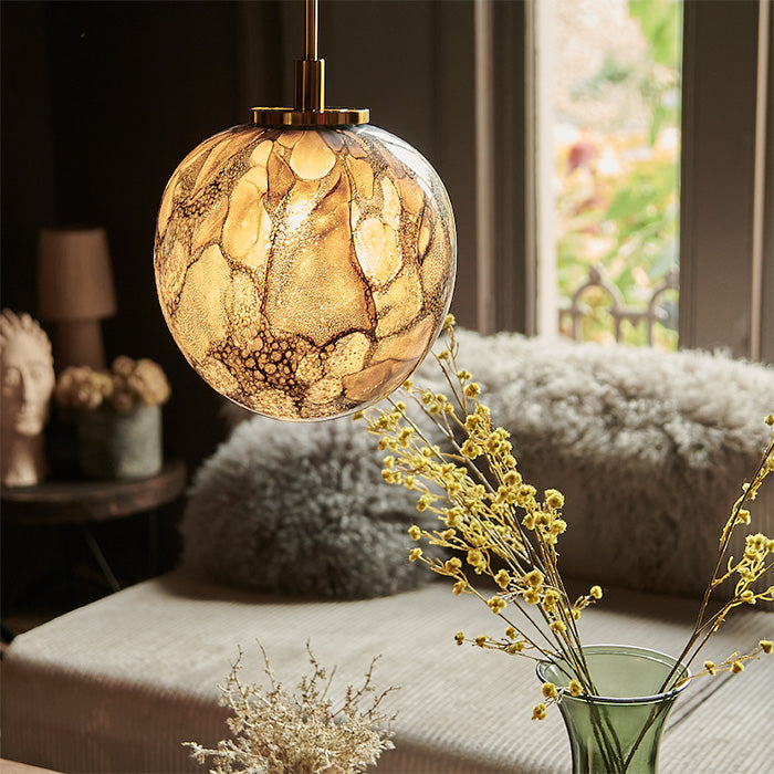 A glass pendant light in a living room with brown painted walls