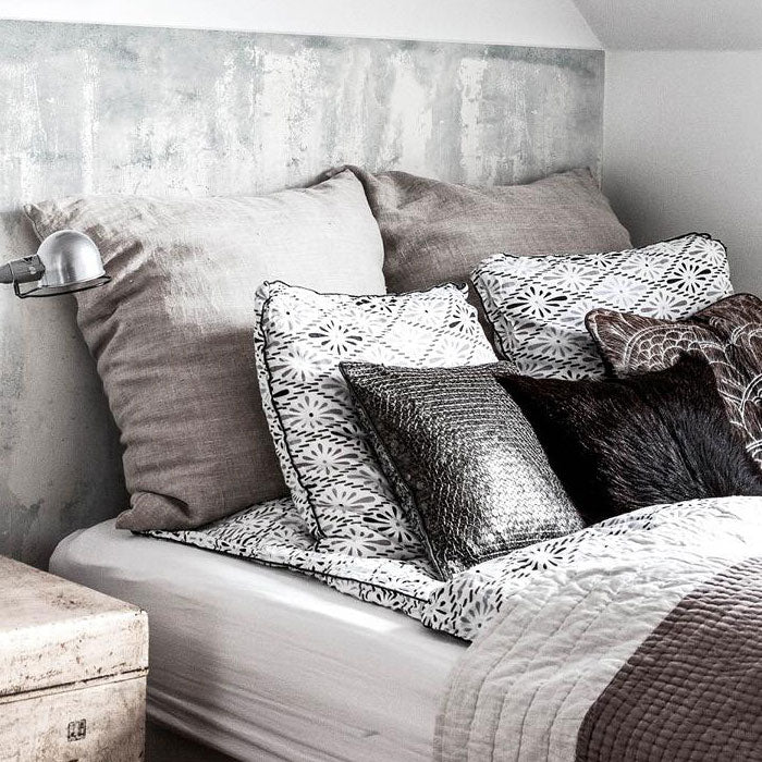 A bed with a faux concrete vinyl wall sticker as a headboard