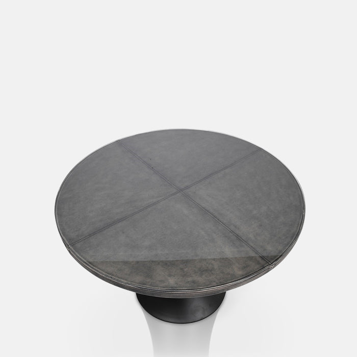 Round dining table wrapped in faux leather and topped with glass 