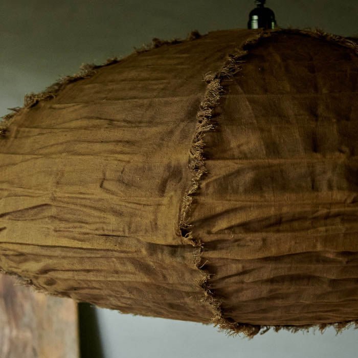 Brown oval fabric pendant shade in a caramel brown colour with tufted edges hanging from a black lamp holder.