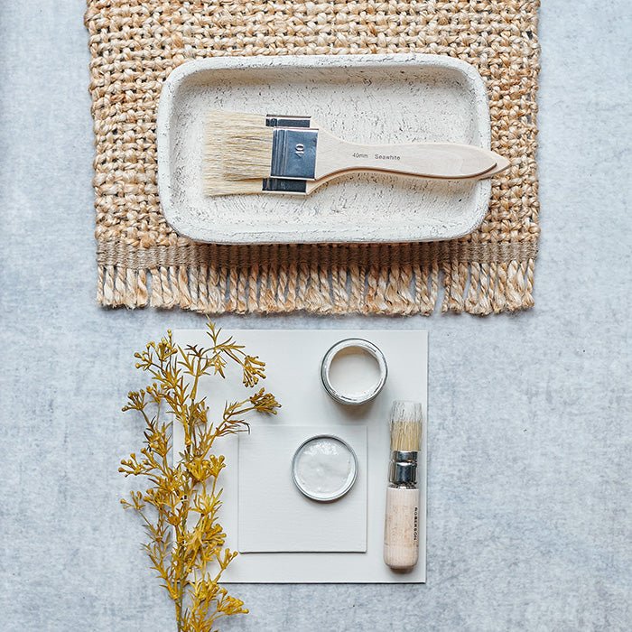Painted swatch in Elder light cream paint colour styled with a faux botanical, natural paintbrush and a natural hessian placemat.