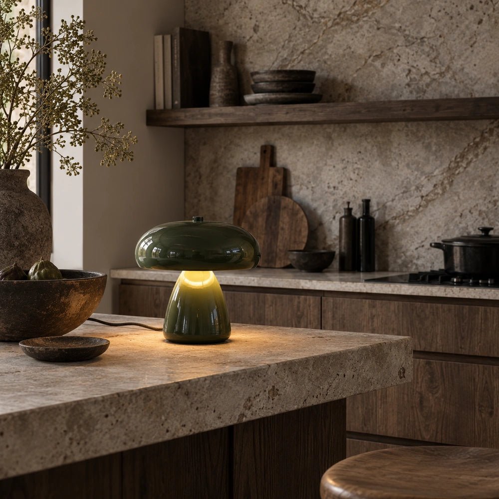 Elmore Metal Table Lamp with rounded olive green shade and compact base, glowing on a stone kitchen island within a warm contemporary kitchen setting.