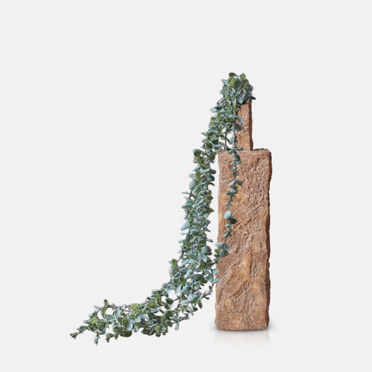 Cutout of the artificial Eucalyptus Trailing coming out of the long, angular Emin Vase with a rough texture and warm terracotta colour.