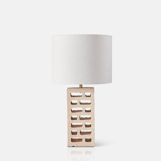 Table lamp with breezeblock-style base and white fabric drum shade.