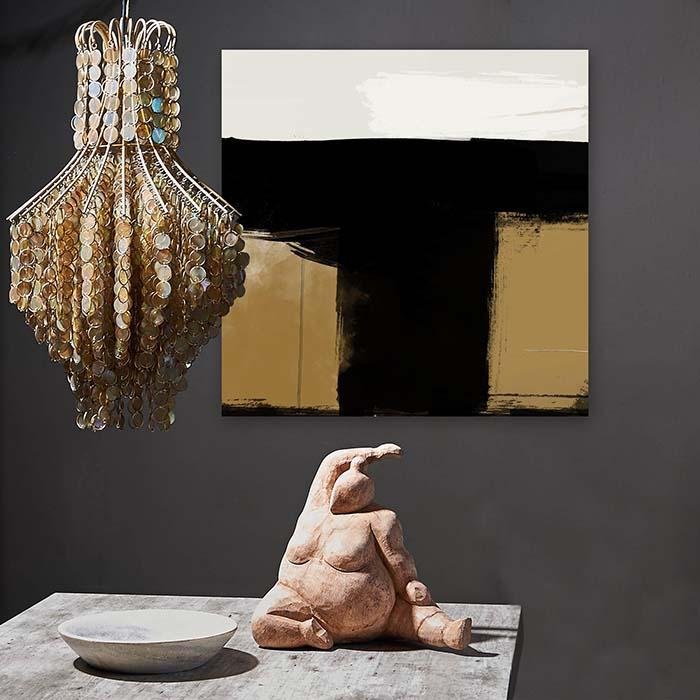 Abstract brushstroke print in black, cream and gold hung behind a chandelier and sculpture