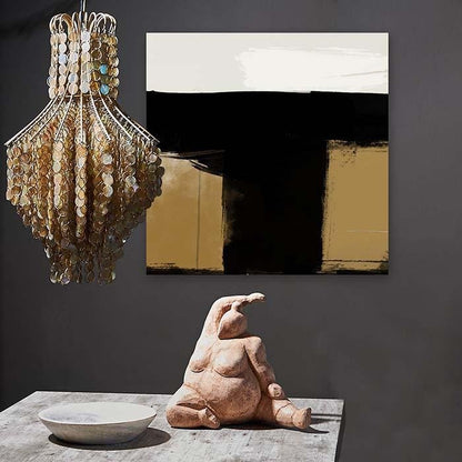 Abstract brushstroke print in black, cream and gold hung behind a chandelier and sculpture
