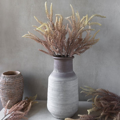 A styled image showing you how to arrange artificial flowers or botanicals in a grey stoneware vase.