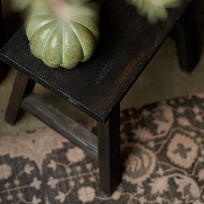 Light and dark brown patterned vinyl flooring underneath a wooden stool