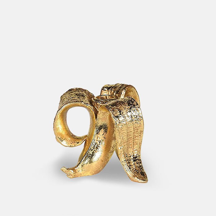 A cutout of Golden Banana Candleholder, a quirky candleholder in resin and finished in gold in the shape of a peeled banana.