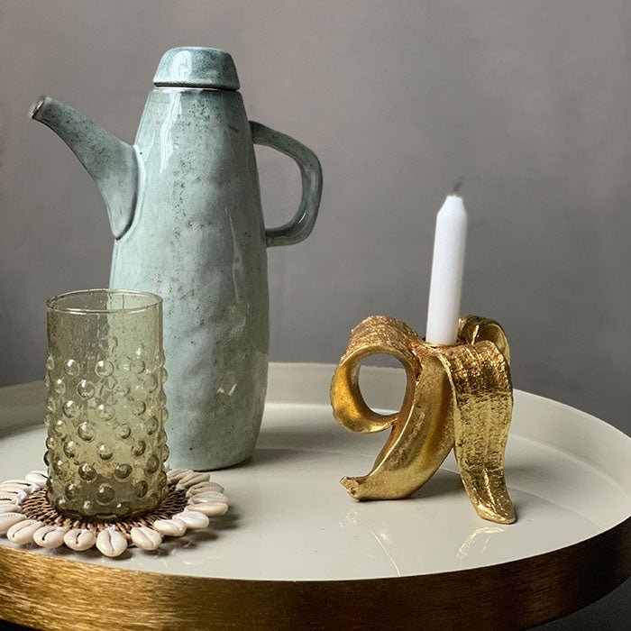 The Golden Banana Candleholder, a quirky candleholder made from resin and finished in gold in the shape of a peeled banana.