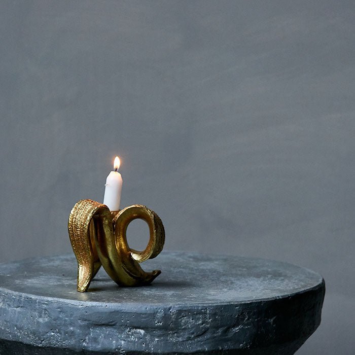 The Golden Banana Candleholder, a quirky candleholder made from resin and finished in gold in the shape of a peeled banana.