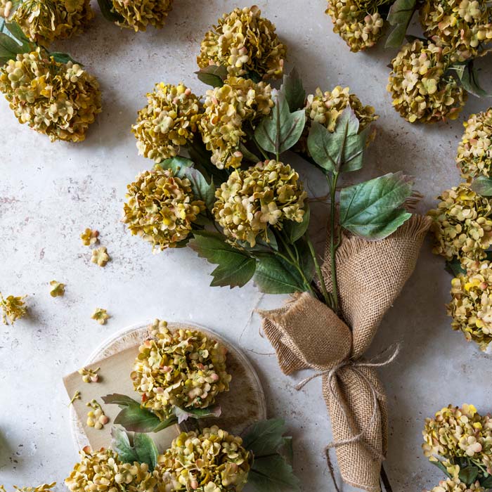 A bouquet of faux guelder rose stems in an earthy yellow colour.