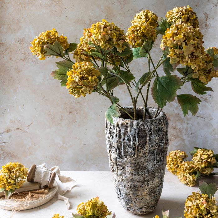 Textural grey vase with a stone like texture with yellow artificial flowers in it