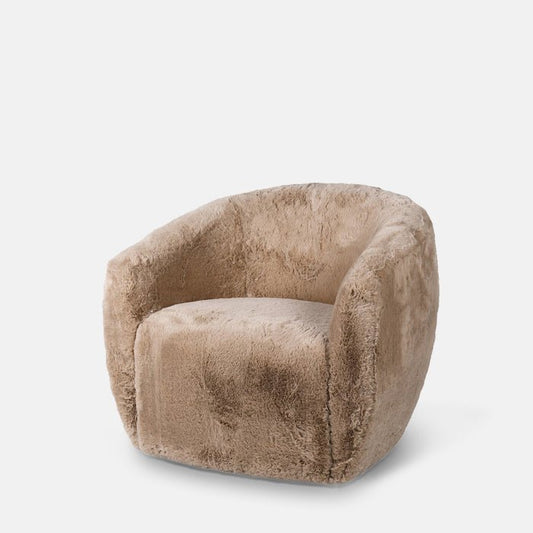 Curved armchair upholstered in cream faux fur fabric.