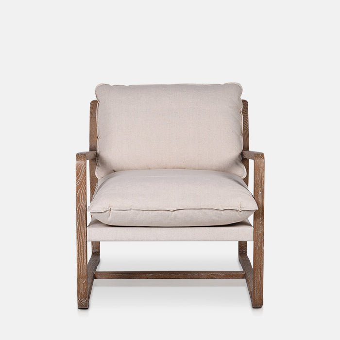 A cutout of the Hockley Armchair, a modernist wooden framed armchair with cream cushioning.
