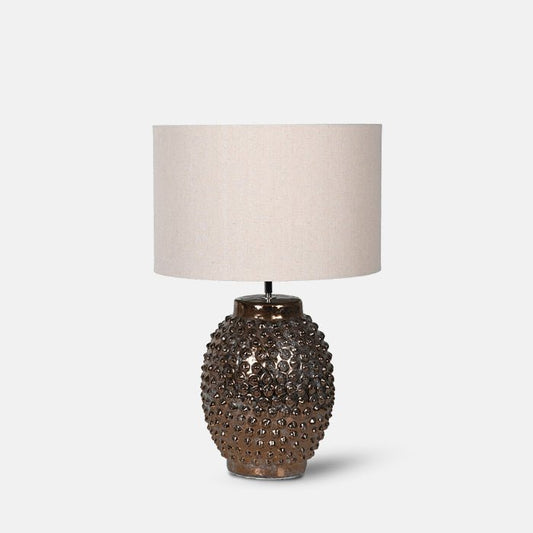 Table lamp with metallic bobble-textured base and large cream drum shade.
