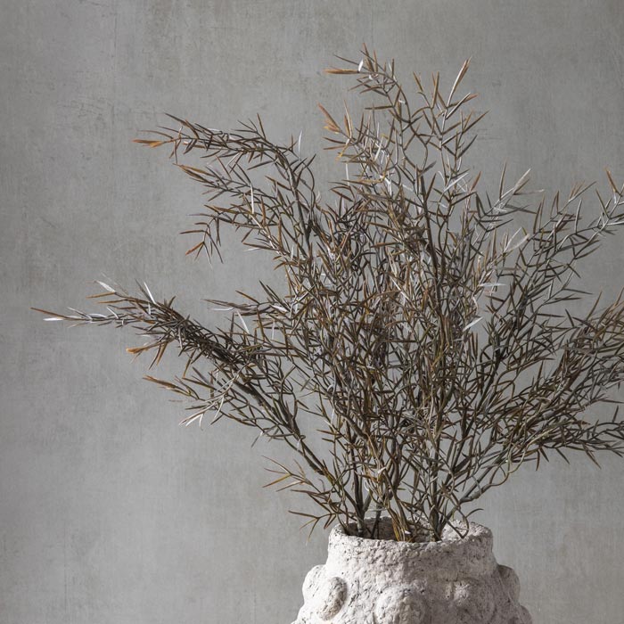 Close up image of Faux Honey Bracelet foliage in a soft green and rust colour in a textured vase. This artificial foliage combines beautifully with other Abigail Ahern botanicals, and is a stunning addition to enhance your space.
