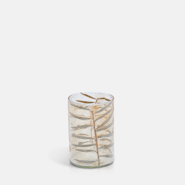 Cylindrical clear glass votive decorated with dried leaves.