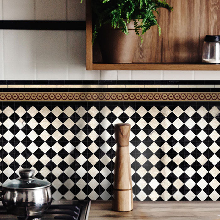 Black and white checkerboard patterned vinyl backsplash stickers along the back of a hob in a kitchen