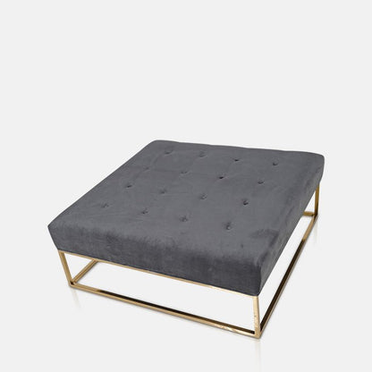 Square cushioned ottoman in grey sat on a raised gold base
