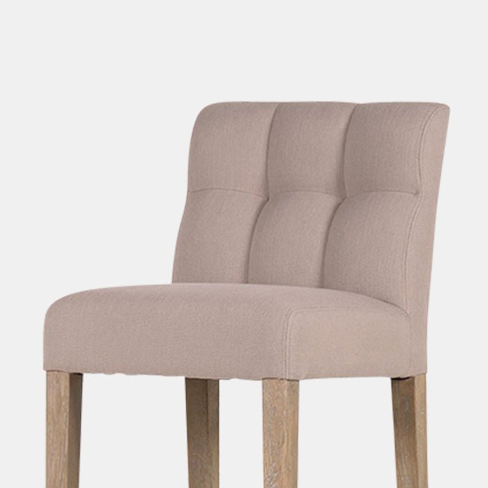 The Kinley Bar Stool, a poly-cotton square seated stool in a taupe hue with slim tapered oak legs.