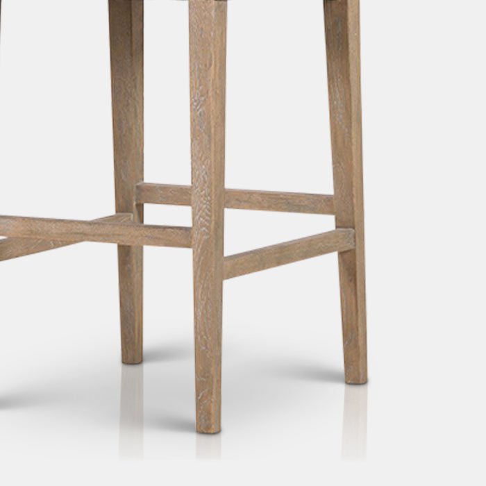 The Kinley Bar Stool, a poly-cotton square seated stool in a taupe hue with slim tapered oak legs.