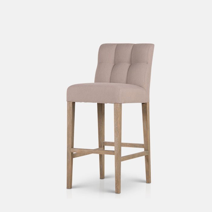 The Kinley Bar Stool, a poly-cotton square seated stool in a taupe hue with slim tapered oak legs.