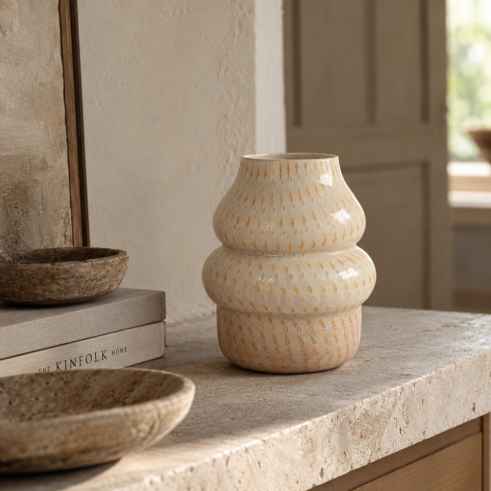 Lagor Glass Vase styled on a pale stone console, showing its rounded stacked silhouette and softly textured cream surface in a warm neutral interior.