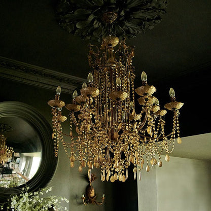 Large ornate glass chandelier with gold frame, hanging from painted black ceiling.