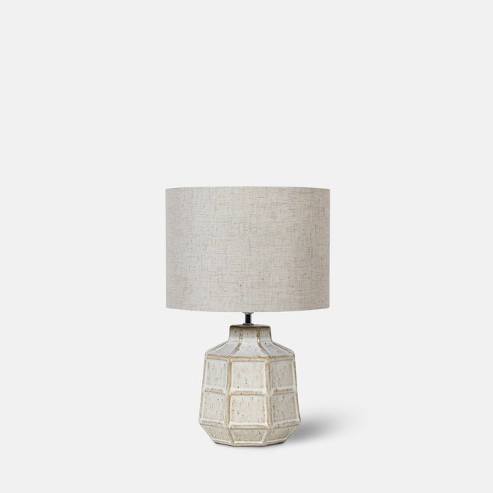 Ceramic grid-patterned table lamp with grey linen shade.