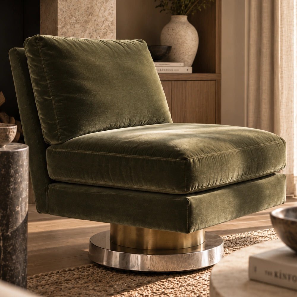 Lilian Velvet Swivel Chair in olive green velvet, shown close up in a warm living room with wood shelving, stone accents and soft natural light.