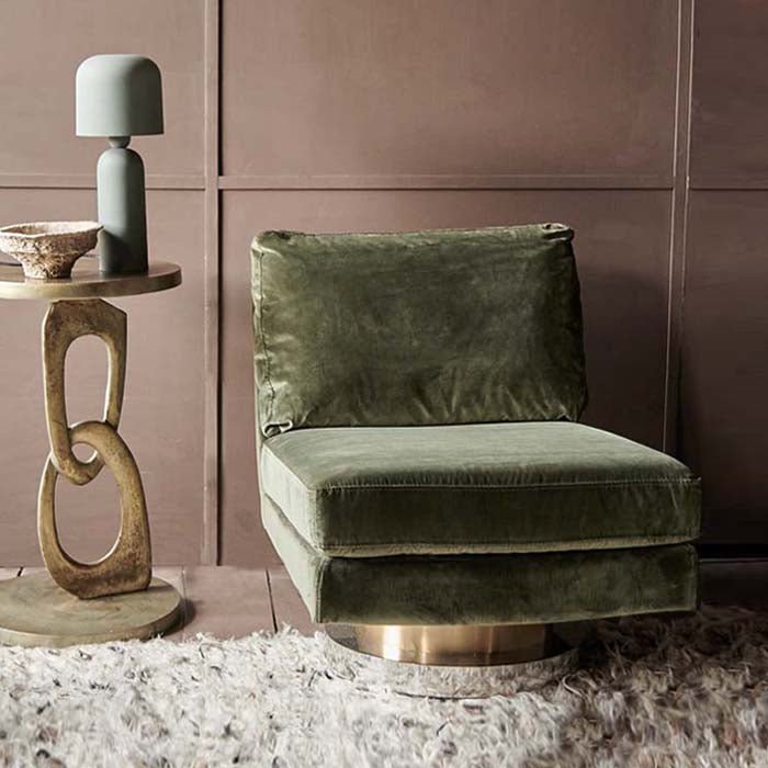 Abigail Ahern Lilian Velvet Swivel Chair in rich olive green velvet, featuring a classic square silhouette with plush cushioning and a contemporary brass-toned pedestal base, styled as a glamorous statement piece in a modern interior.
