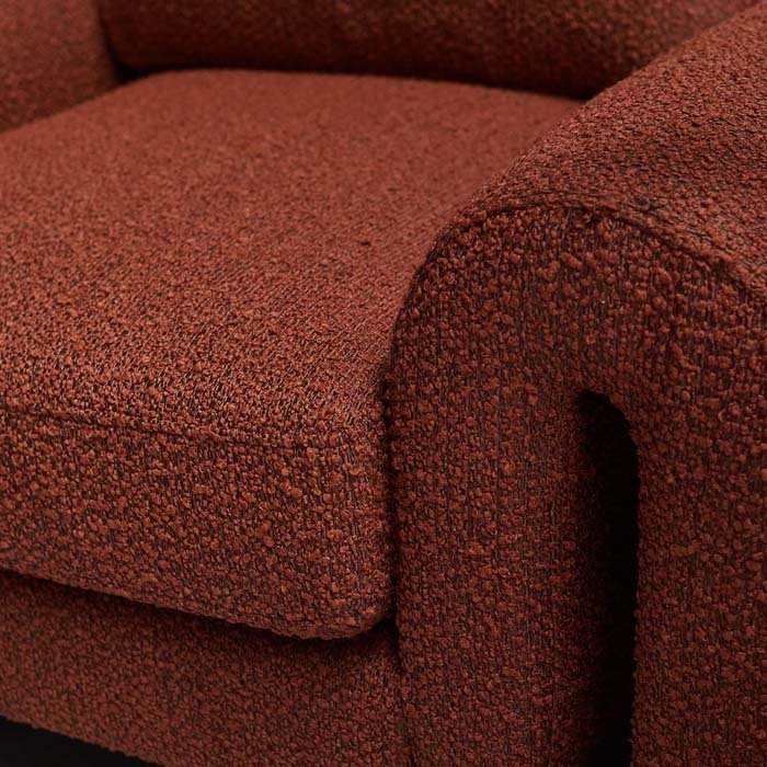 Close-up of the Abigail Ahern Manhattan Boucle Armchair in rust, highlighting the curved sculptural shape and richly textured boucle upholstery with its soft, tactile finish.
