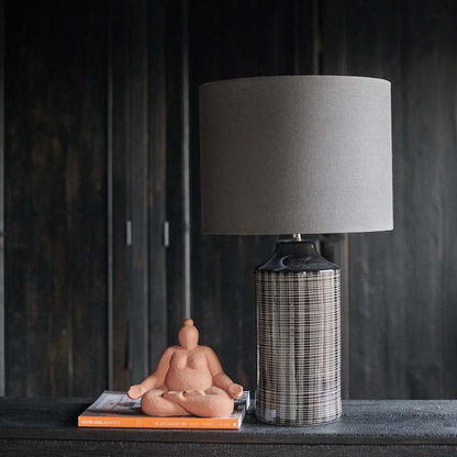 Tall grey table lamp with a grey lamp shade next to a coral figurine 