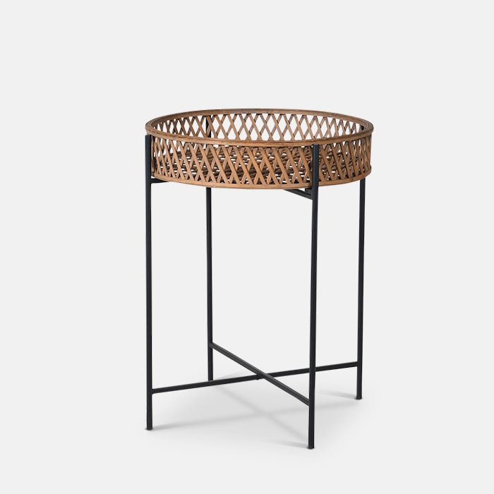A cutout of the Marino Rattan Side Table, a round rattan tray table with slim black legs.