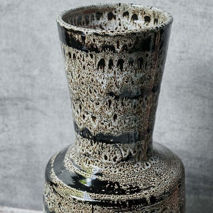 Close up of the Matumbo Vase, a black and cream sculptural reactive glazed ceramic vase with a speckled and striped pattern.