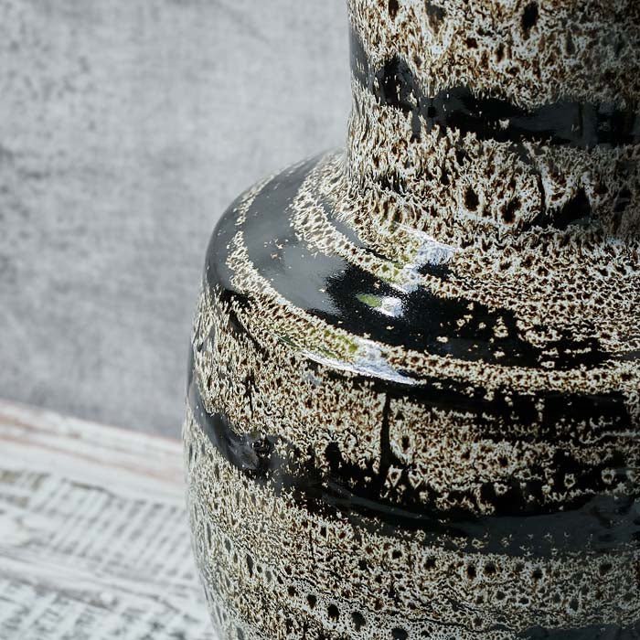 Close up of the Matumbo Vase, a black and cream sculptural reactive glazed ceramic vase with a speckled and striped pattern.