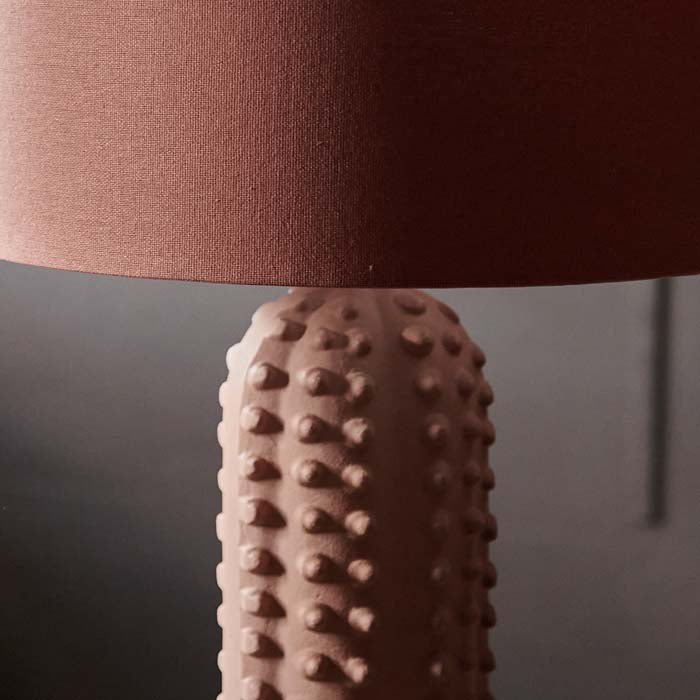 A close up of the Maynard Table. A coral hued linen shade and a bubble textural ceramic matte base table lamp.