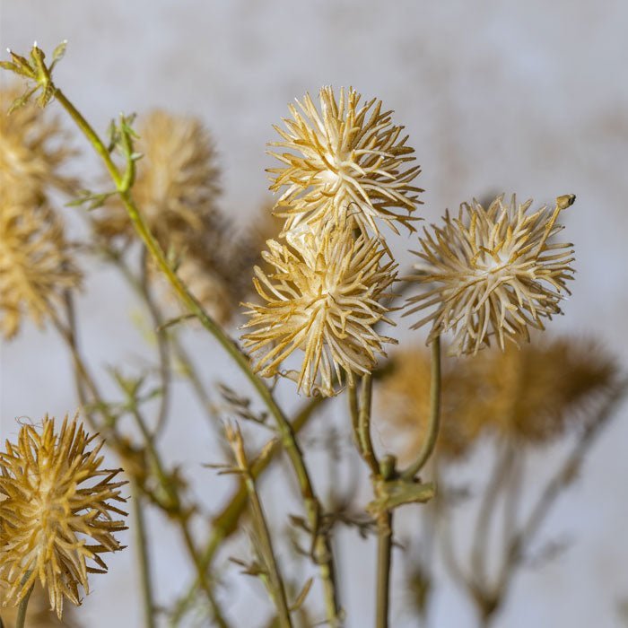 Detail of the orange spiky heads of a faux meadow pom pom stem.